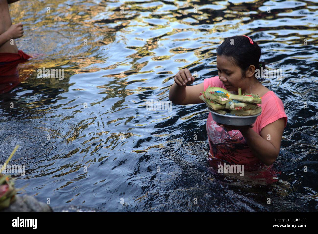 Une femme préparant une offrande à la piscine du temple de Tirta Empul à Tampaksiring, Gianyar, Bali, Indonésie. L'eau est considérée comme sainte à Bali. Banque D'Images