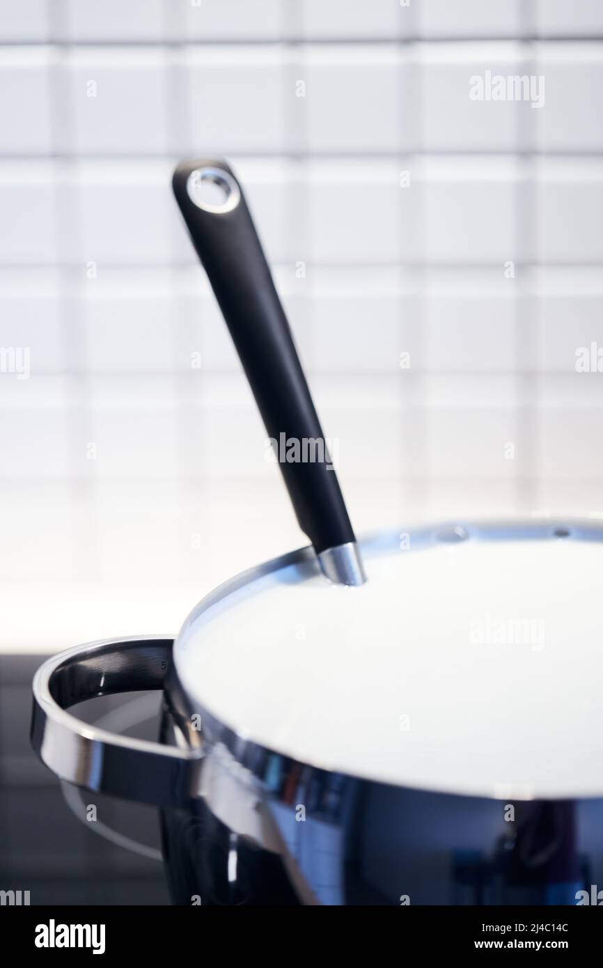Le processus de fabrication du yaourt. Le lait est chauffé et fermenté par des bactéries. Lait dans une casserole sur la cuisinière. Photo verticale. Banque D'Images