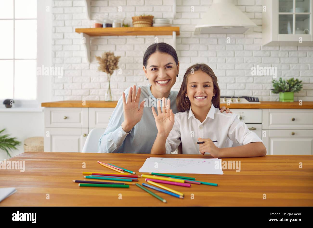Une mère et un enfant heureux agitant leurs mains à la caméra en classe en ligne par appel vidéo Banque D'Images
