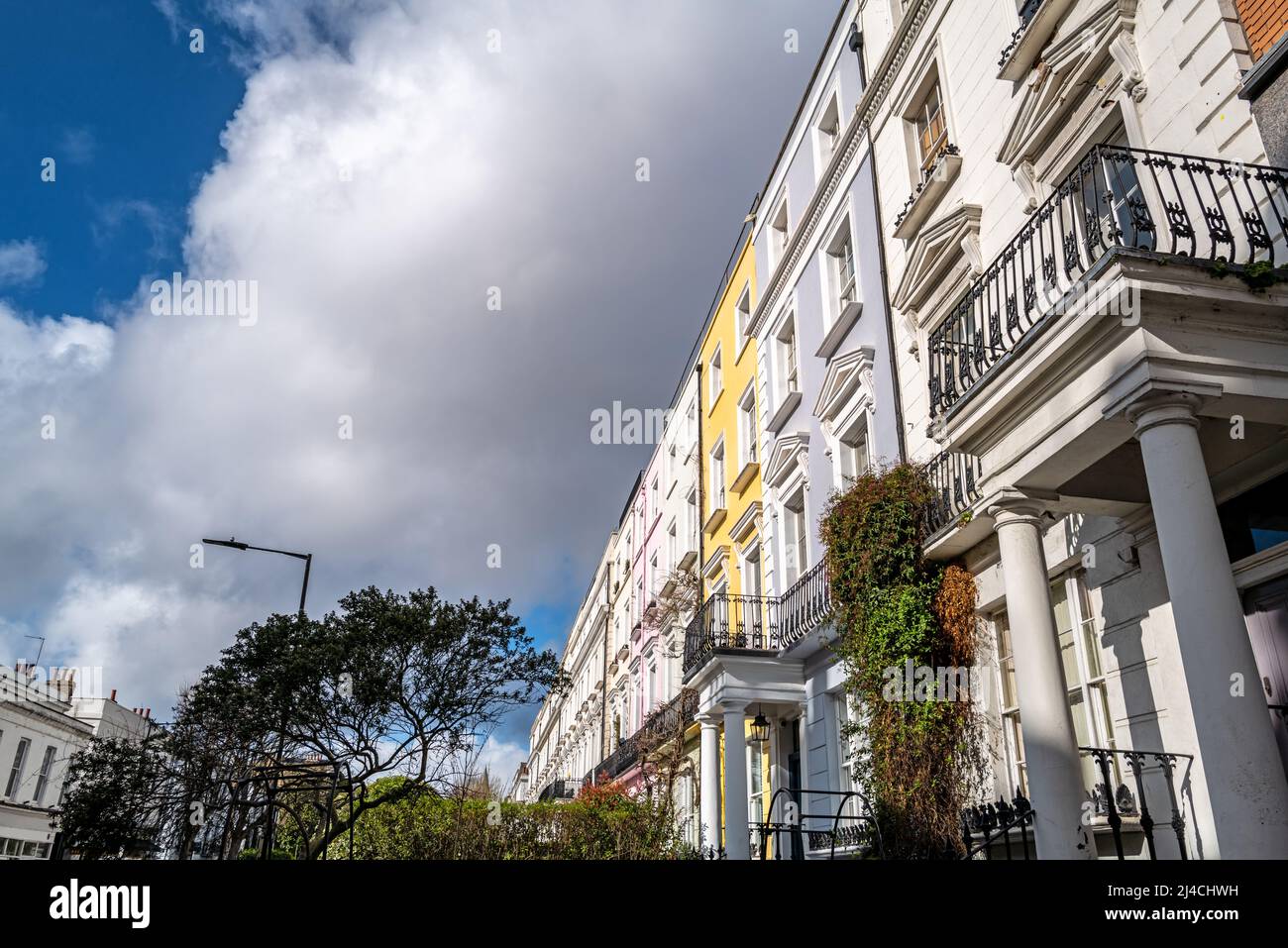 Maisons mitoyennes colorées avec ciel d'été et arbres. Le quartier de Notting Hill, Londres, est célèbre pour ses rues de maisons aux couleurs vives Banque D'Images
