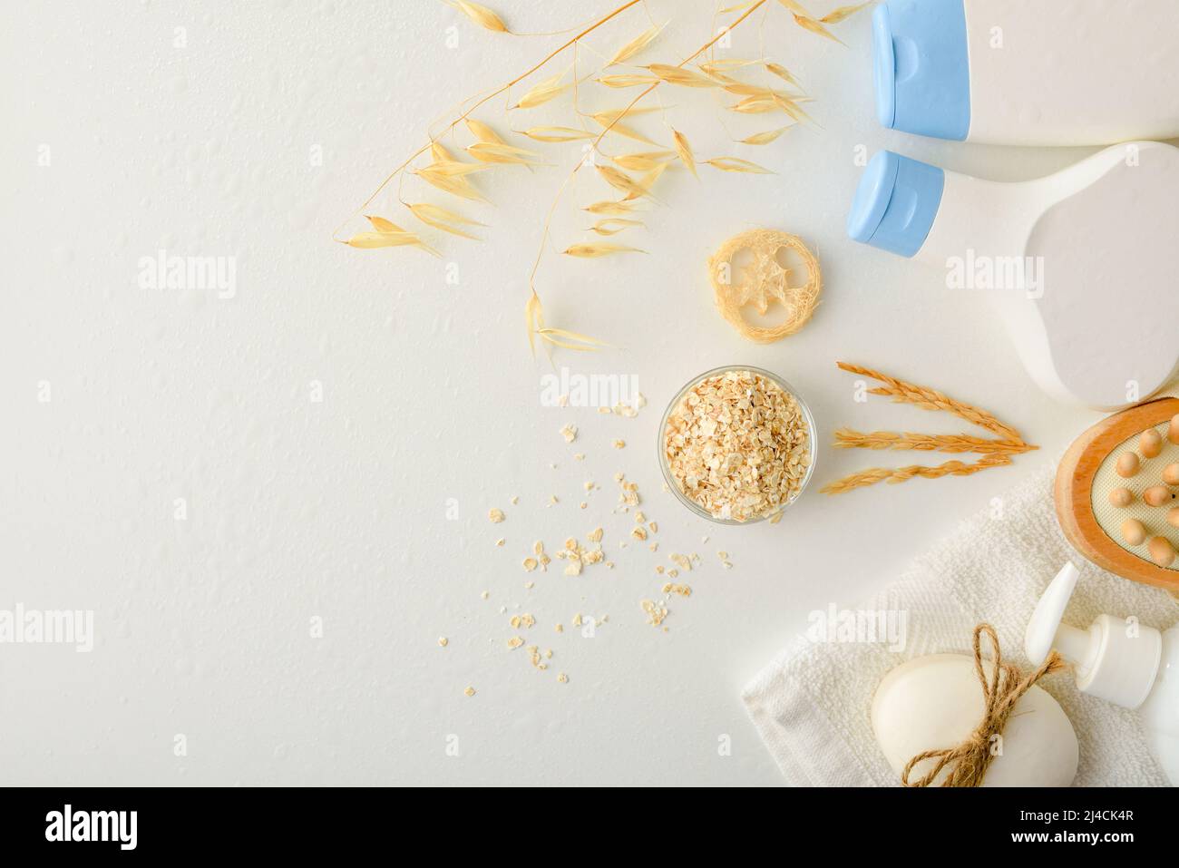 Détail des produits de douche avec extrait d'avoine avec pailles et flocons sur table blanche. Vue de dessus. Composition horizontale. Banque D'Images