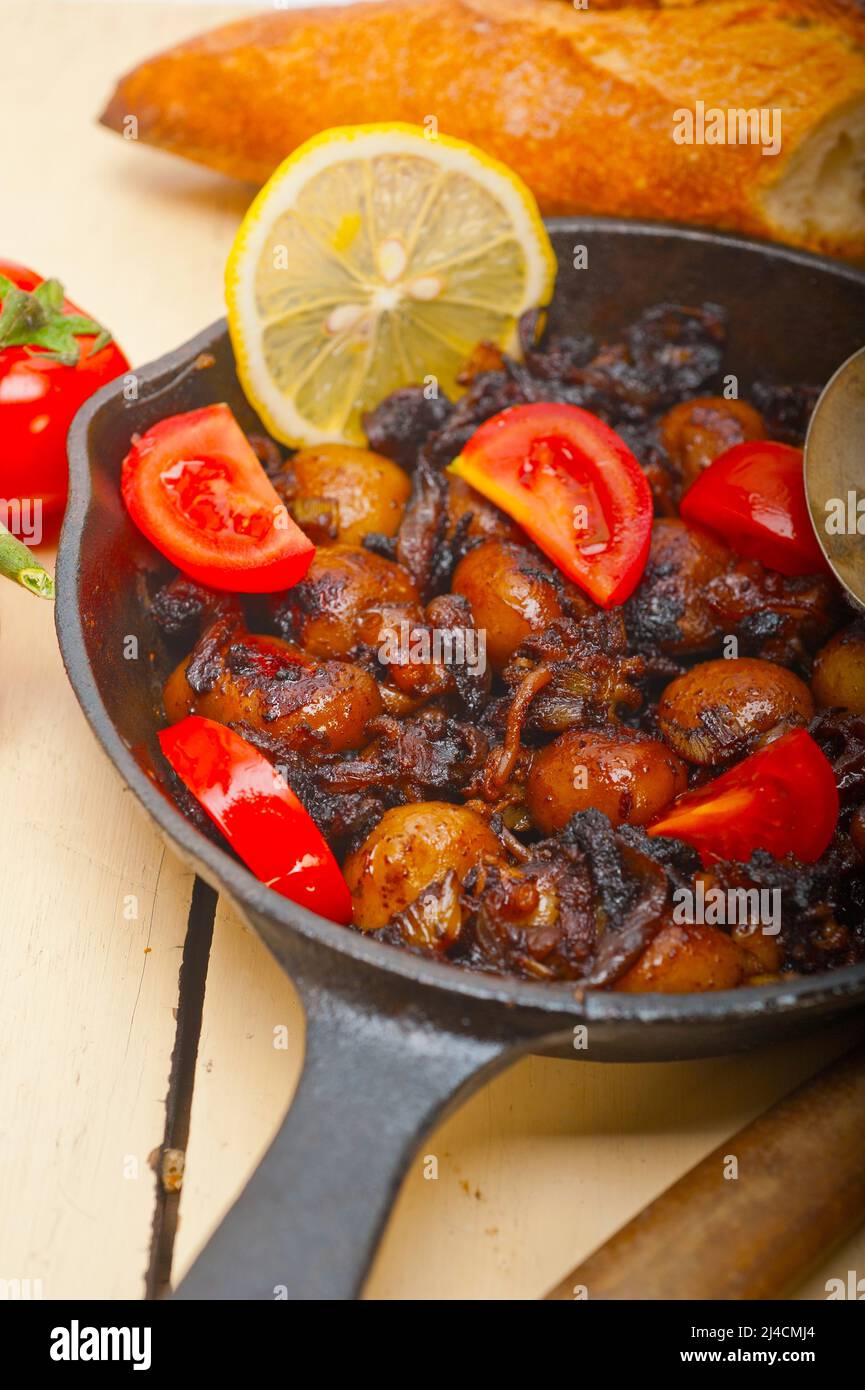 Seiches bébé rôti sur iron skillet avec les tomates et les oignons sur table en bois rustique Banque D'Images