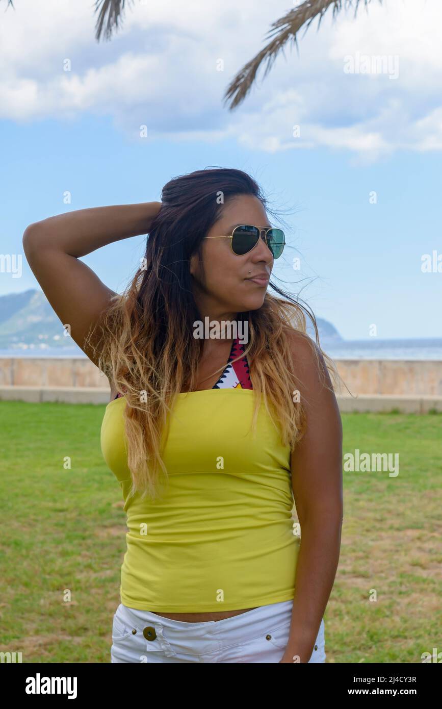 portrait d'une femme latine souriant, s'amusant, en vacances à majorque posant sur une chaude journée de printemps d'été, sous un palmier, concept de vacances Banque D'Images