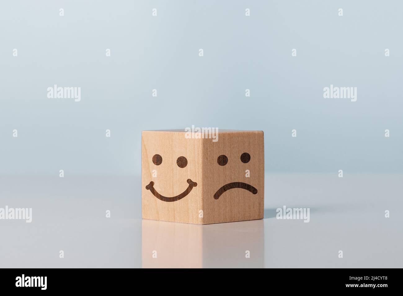 Évaluation du service, classement, avis client, satisfaction et concept d'émotion. Bloc en bois avec visage heureux et malheureux. Les icônes d'émoticônes font face à Wooden Cu Banque D'Images