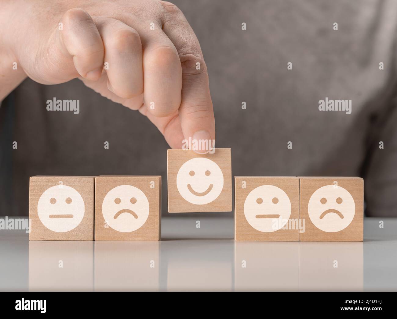 Évaluation du service à la clientèle et concepts d'enquête de satisfaction. Le client a choisi le visage heureux visage sourire symbole sur des blocs de bois. Les icônes d'émoticônes se trouvent sur le visage Banque D'Images