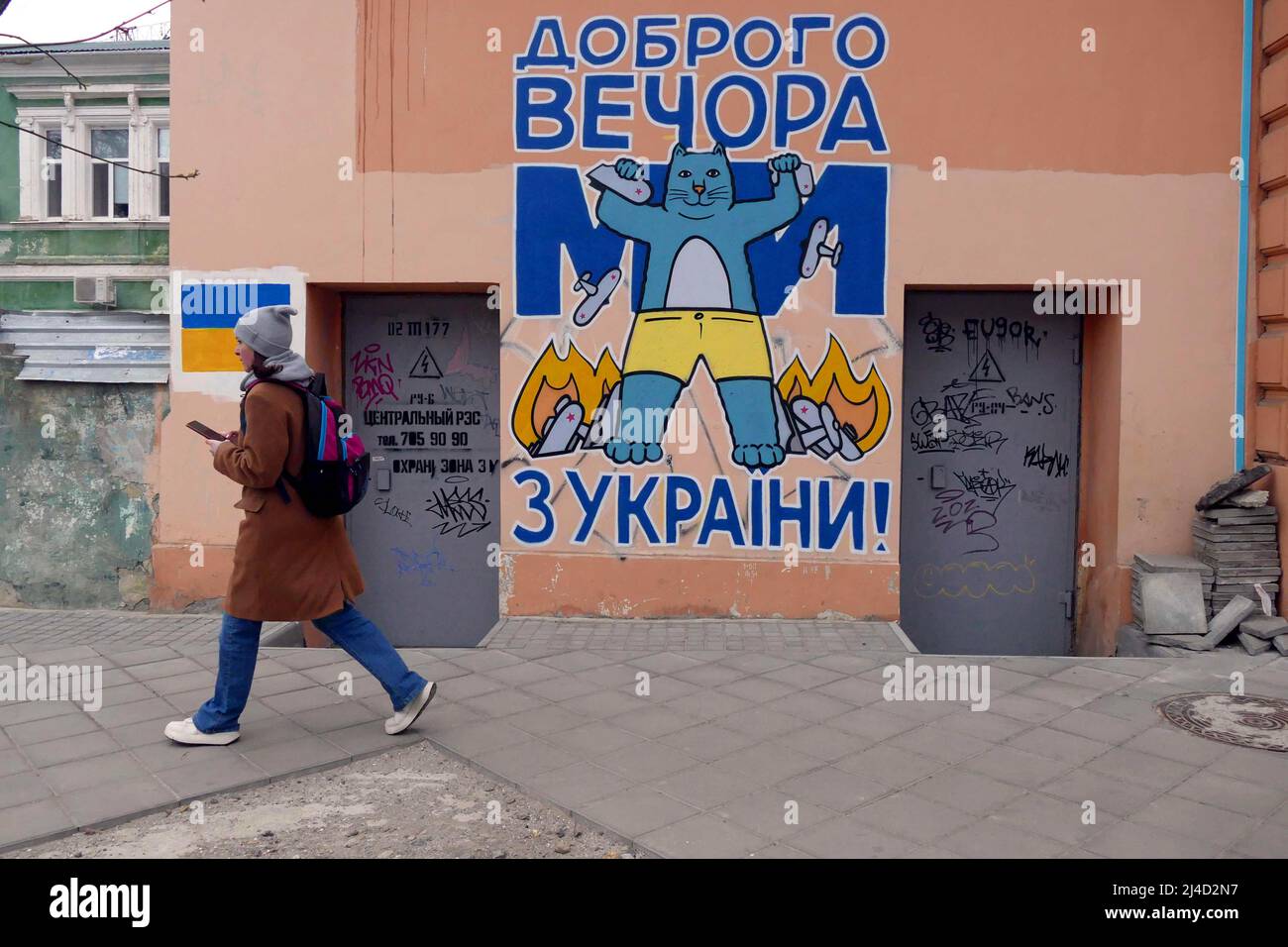ODESA, UKRAINE - 11 AVRIL 2022 - Une femme passe devant l'une des peintures murales peintes par l'artiste local Ihor Matroskin qui présente un chat avec l'expression 'Goo Banque D'Images
