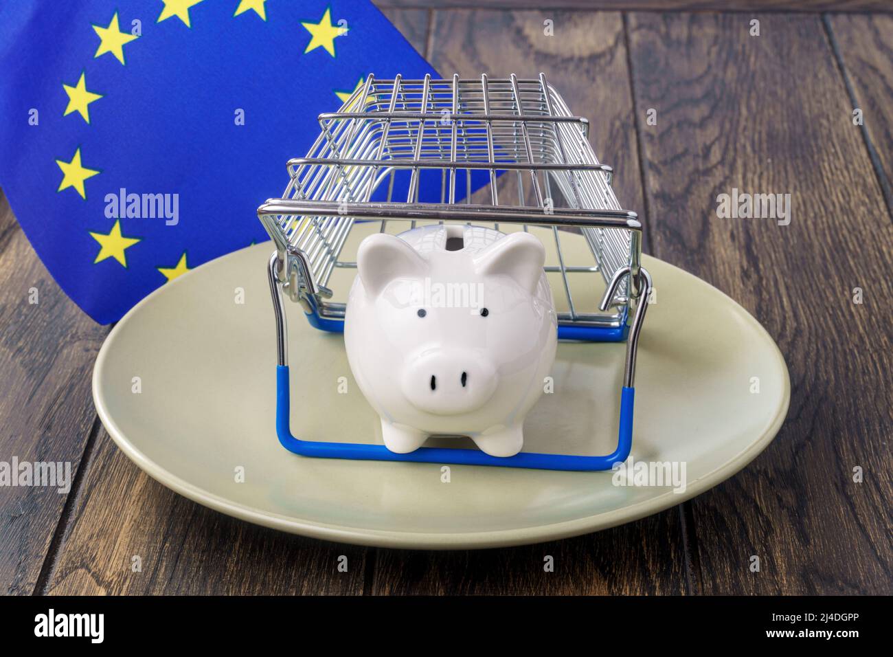 Tirelire sur une assiette sous le panier et le drapeau de l'Union européenne. Concept d'inflation alimentaire Banque D'Images