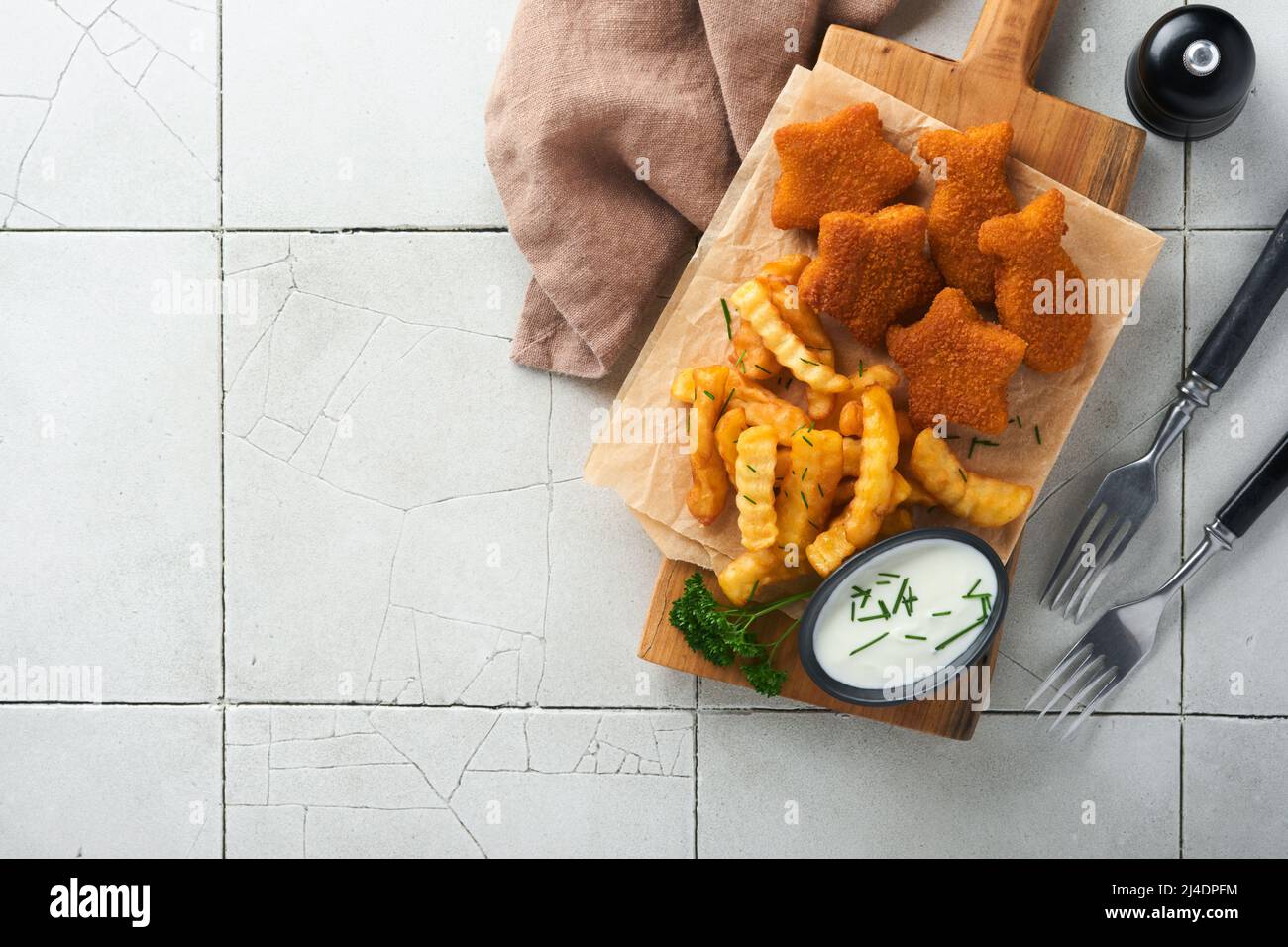 Fish Chips, restauration rapide britannique. Les bâtonnets de poisson aux frites sont fixés sur un panneau rustique, sur un fond de table de comptoir en carreaux gris craquelés. Tradition Banque D'Images