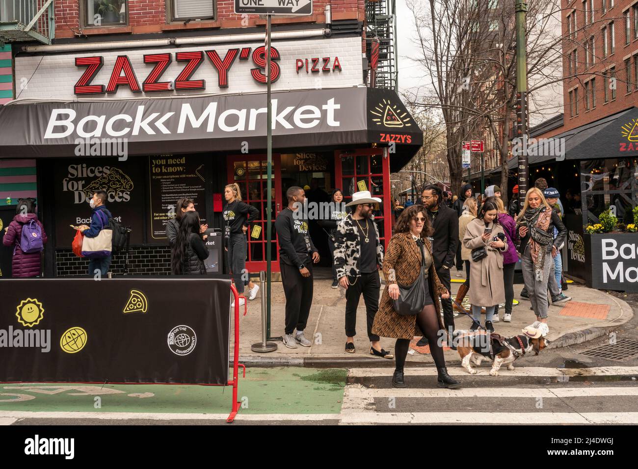 Les gens affluent vers Zazzy’s Pizza, dans le quartier du Lower East Side de New York, pour participer à la promotion « Slices for Devices » de Backmarket, le samedi 9 avril 2022. Backmarket, un revendeur de technologies d'occasion, achète des téléphones intelligents éligibles d'occasion en donnant de l'argent sur place. Les propriétaires de téléphones non admissibles peuvent les échanger contre des tranches de pizza et d'autres friandises. (© Richard B. Levine) Banque D'Images