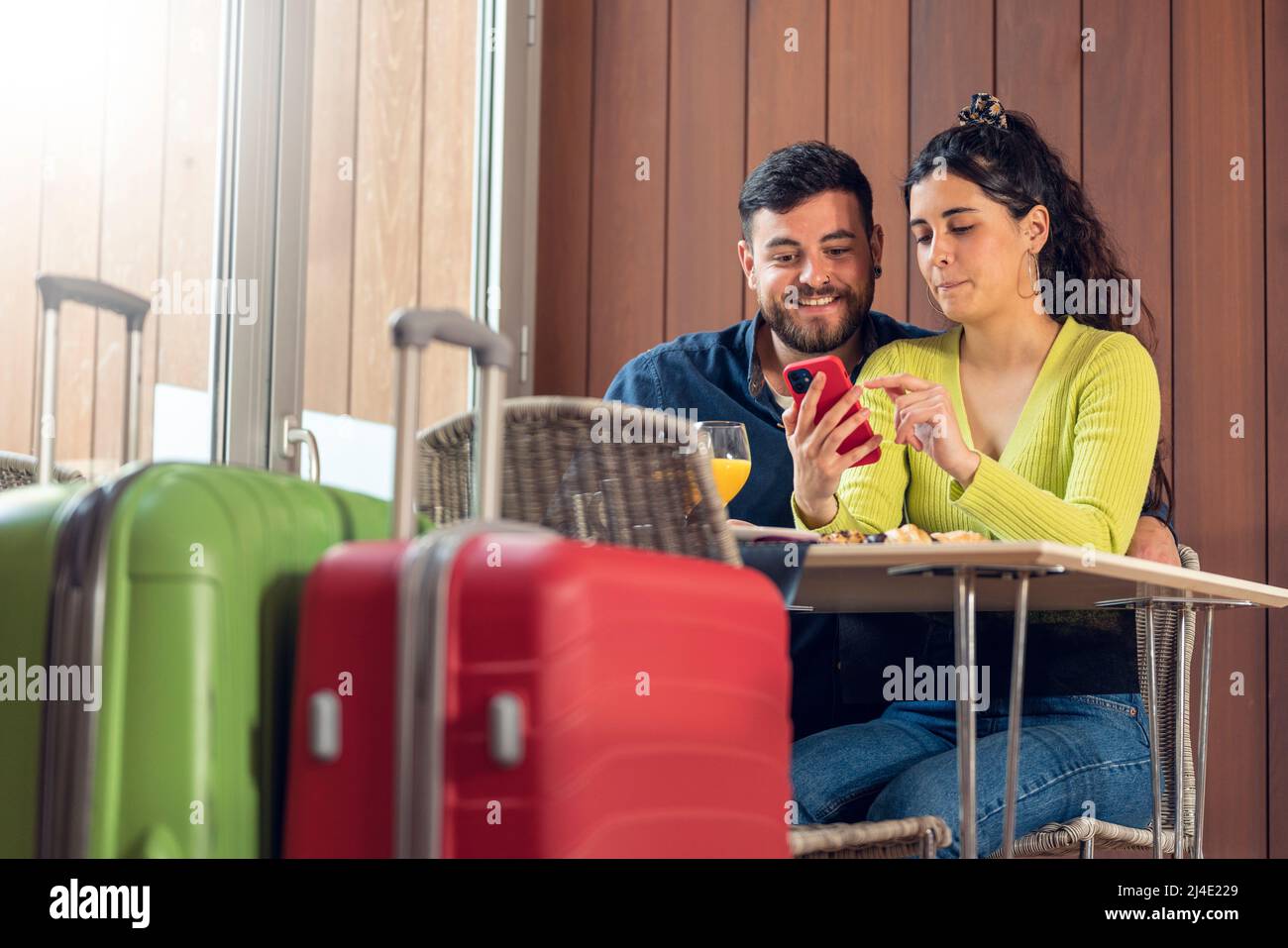 Couple touristique regardant le téléphone et prenant le petit déjeuner dans un restaurant de l'hôtel Banque D'Images