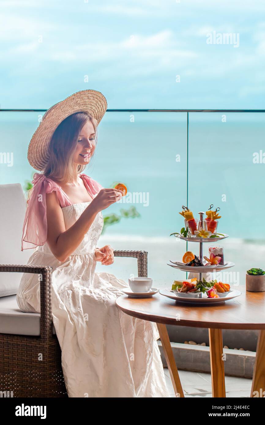 Thé l'après-midi dans un restaurant de luxe avec vue sur la mer. Femme élégante mangeant des fruits Banque D'Images