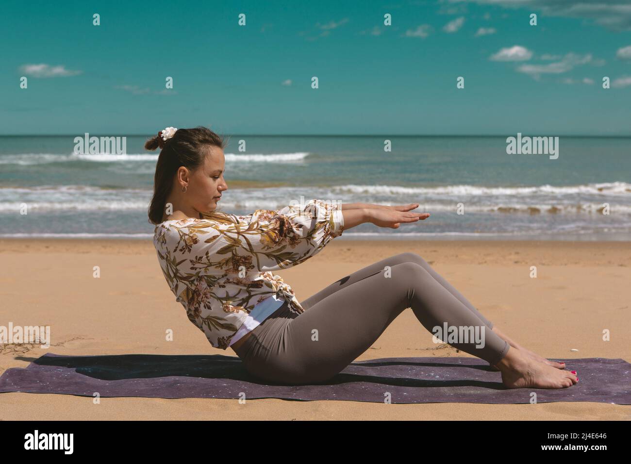 athlète féminine effectuant un exercice de pilates sur la plage Banque D'Images