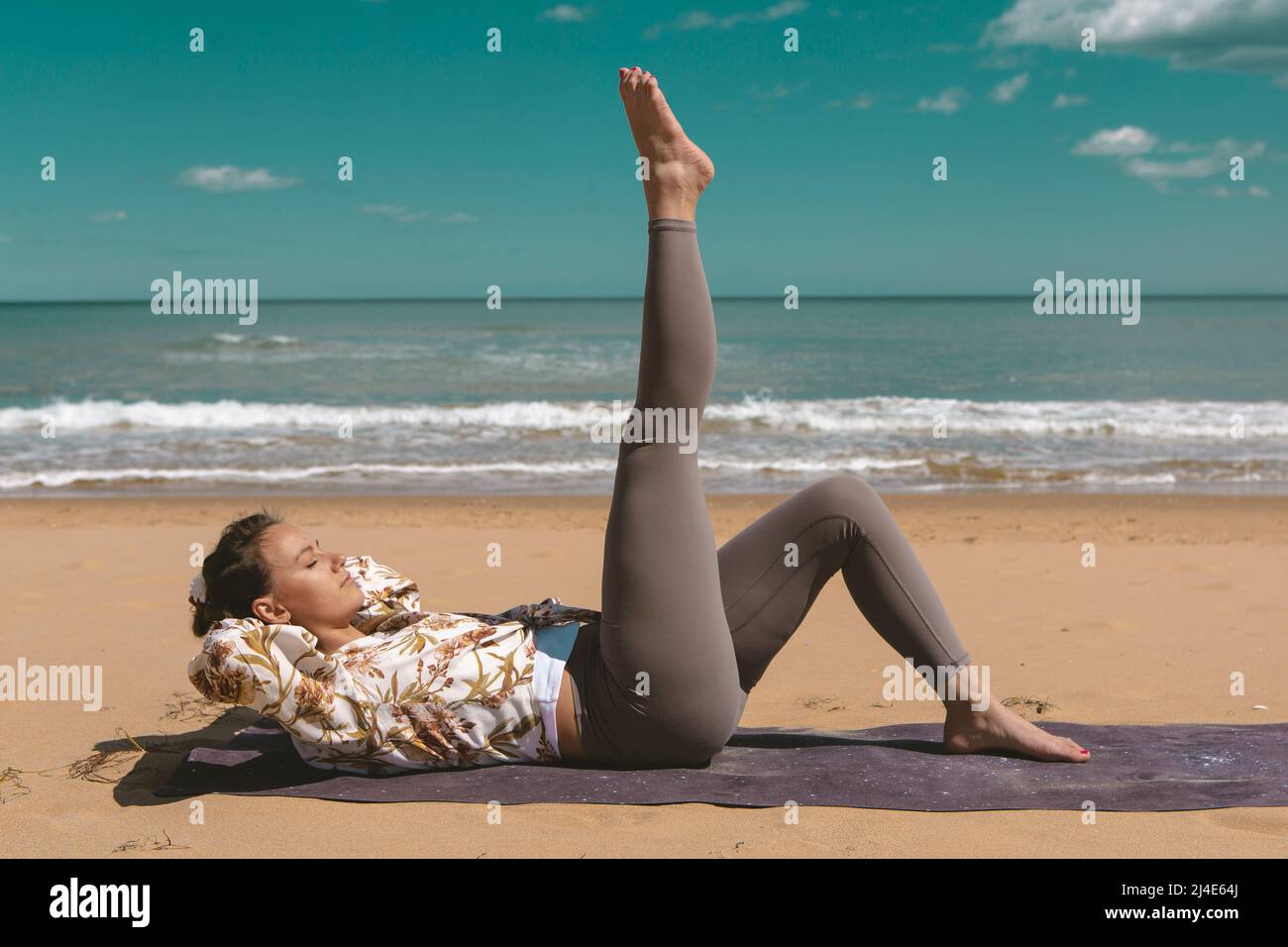 athlète féminine effectuant un exercice de pilates sur la plage Banque D'Images