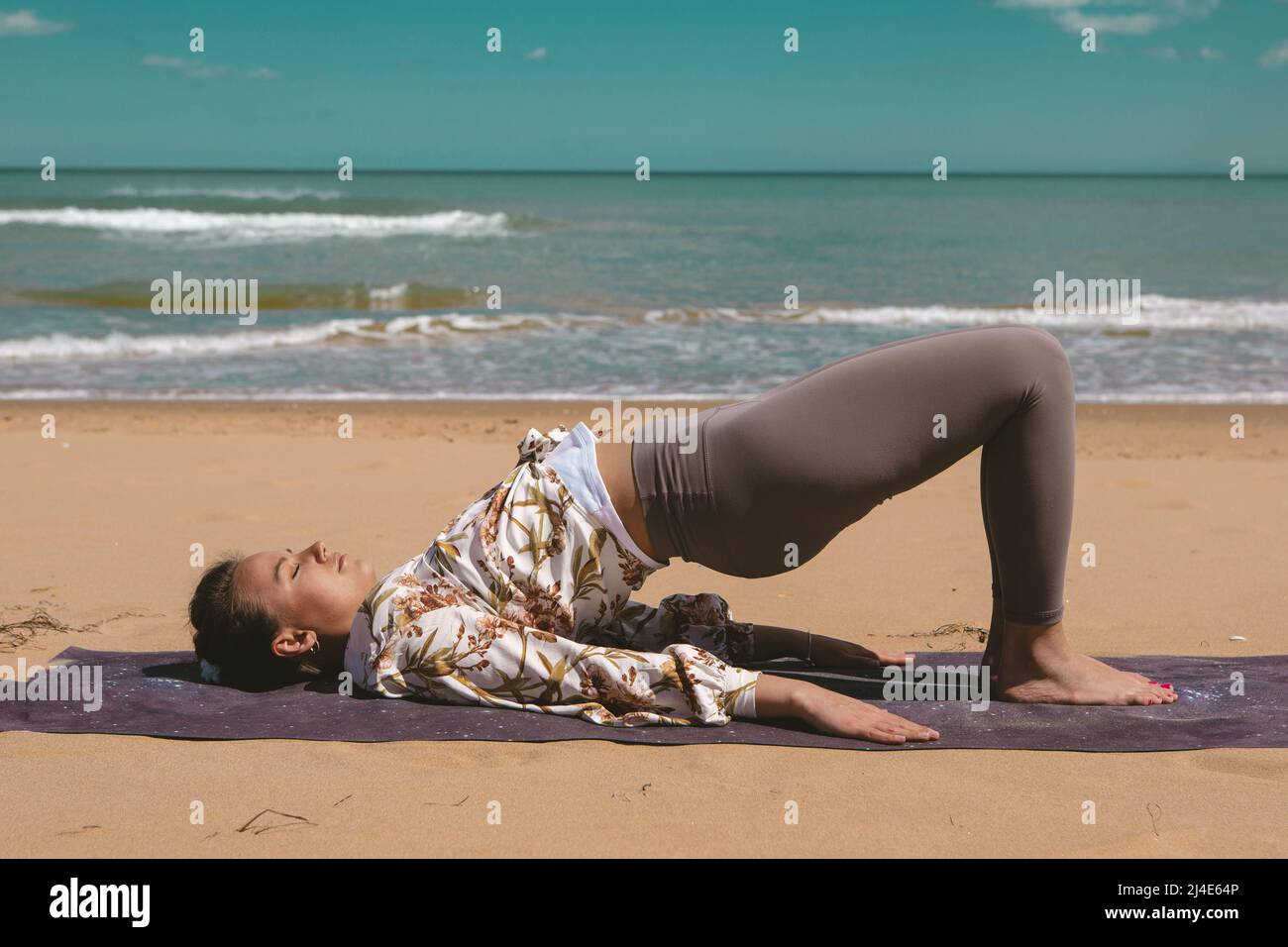 jeune femme faisant de l'exercice pilates sur la plage Banque D'Images