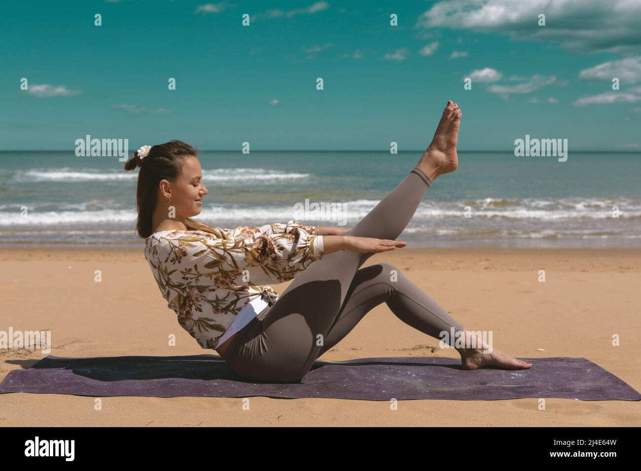 jeune femme faisant de l'exercice pilates sur la plage Banque D'Images