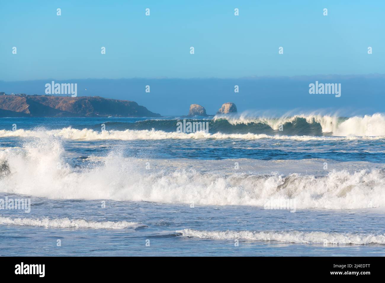 Vagues freinant sur la plage de Pichilemu avec les falaises de Punta de Lobos à l'arrière, région VI, Chili Banque D'Images Vagues freinant sur la plage de Pichilemu avec les falaises de Punta de Lobos à l'arrière, région VI, Chili Banque D'Images