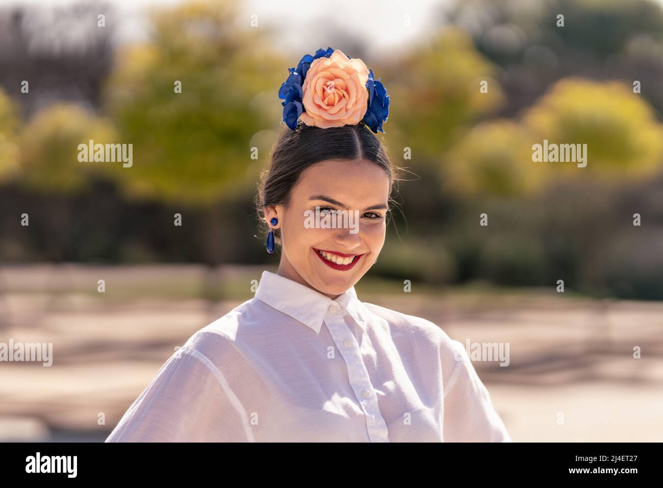 Portrait d'une jeune danseuse de flamenco souriante avec de grandes décorations florales colorées sur sa tête Banque D'Images