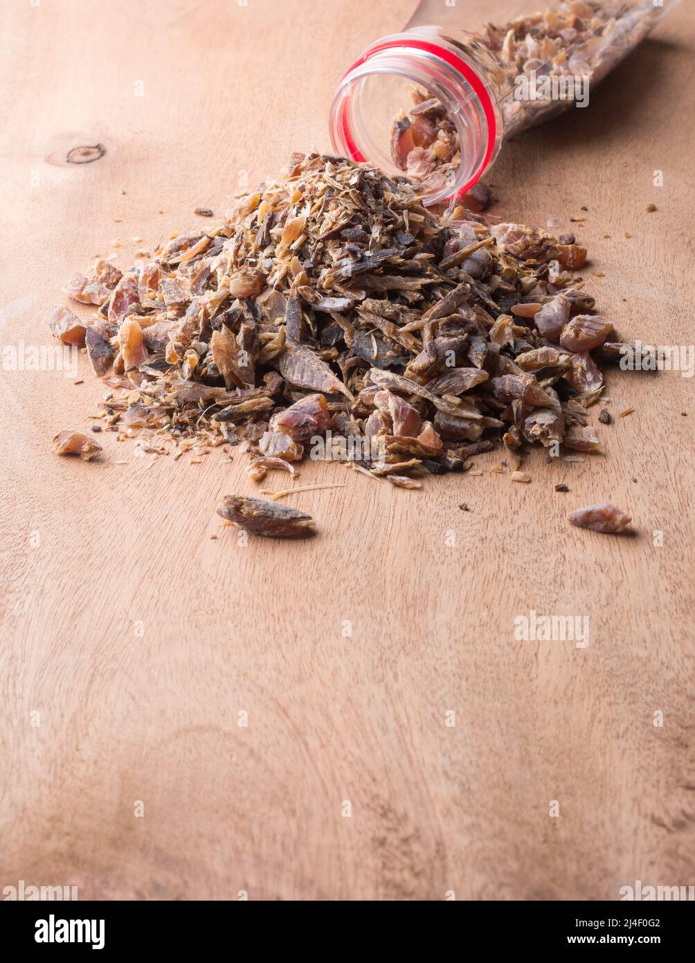 copeaux de poisson maldive, dispersés sur une surface en bois de son contenant, morceaux de poisson séchés et séchés, saveur forte et ingrédient aromatique Banque D'Images