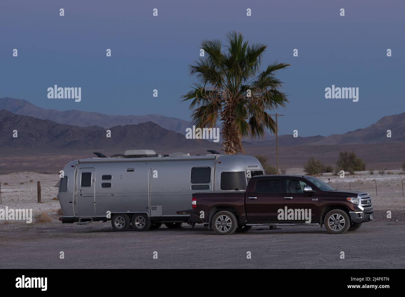 Airstream remorque et camionnette montrées dans le désert de Mojave au lever du jour. Banque D'Images