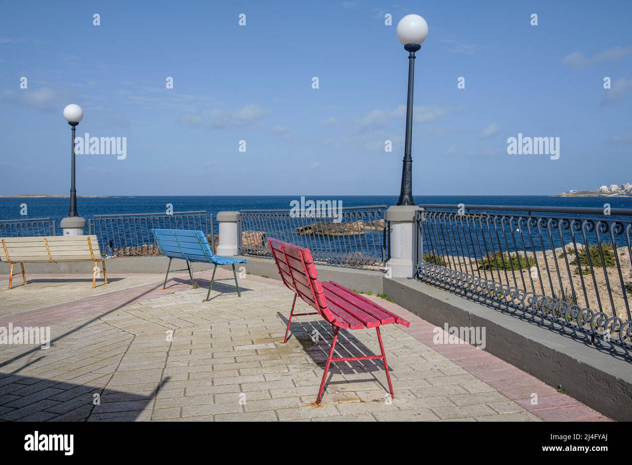 Bancs peints en couleurs sur le front de mer déserté de la baie de St Paul hors saison, Malte Banque D'Images