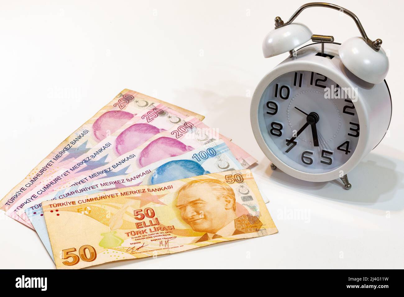 50, 100 et 200 billets turcs et réveil sur fond blanc isolé. Le temps, c'est de l'argent. Banque D'Images