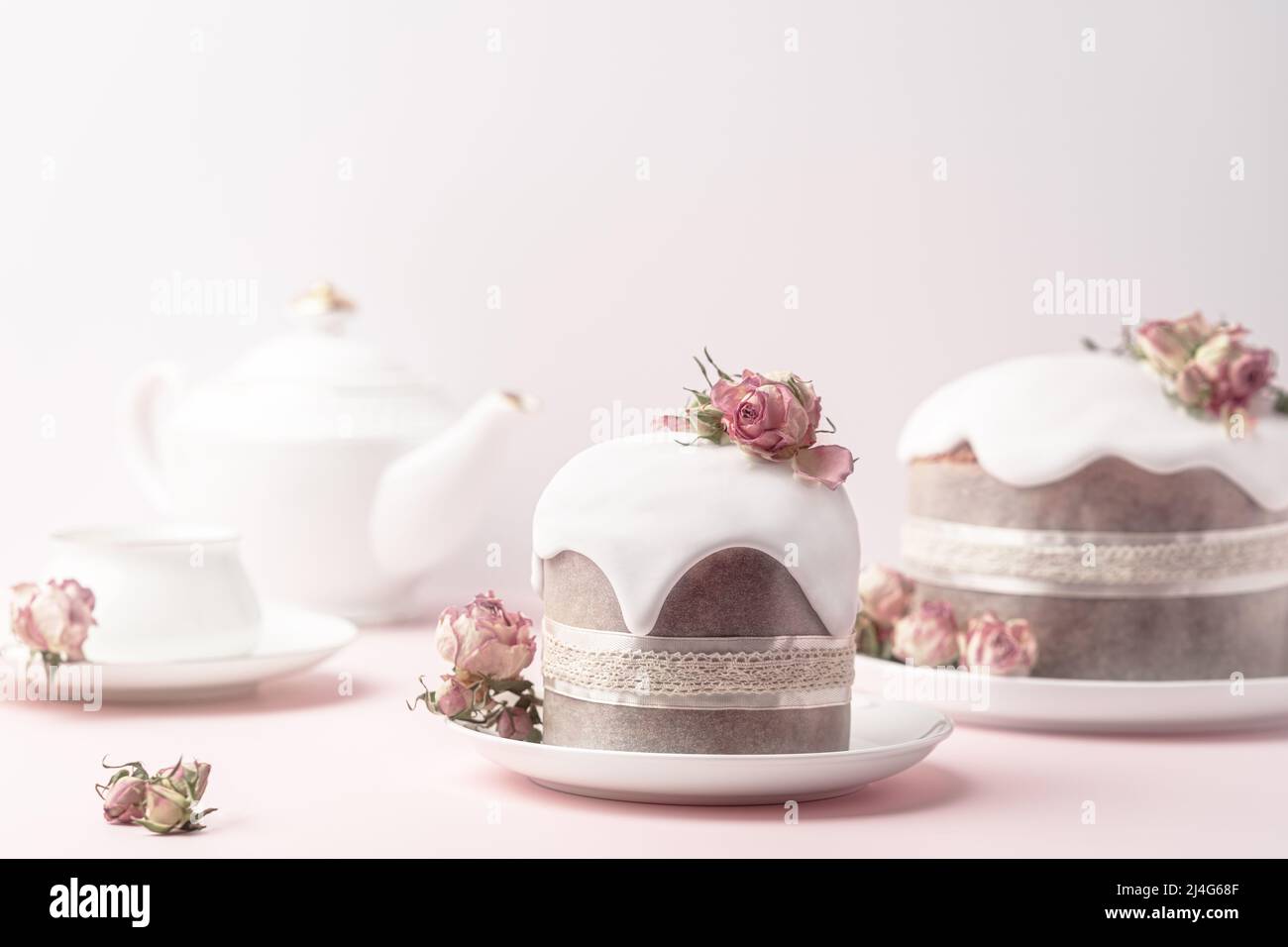 Gâteaux de Pâques émaillés décorés de fleurs de rose de thé sur fond rose pastel. Composition de Pâques avec gâteaux, roses et œufs au chocolat. Arrière-plan de vacances avec espace de copie pour votre conception. Banque D'Images