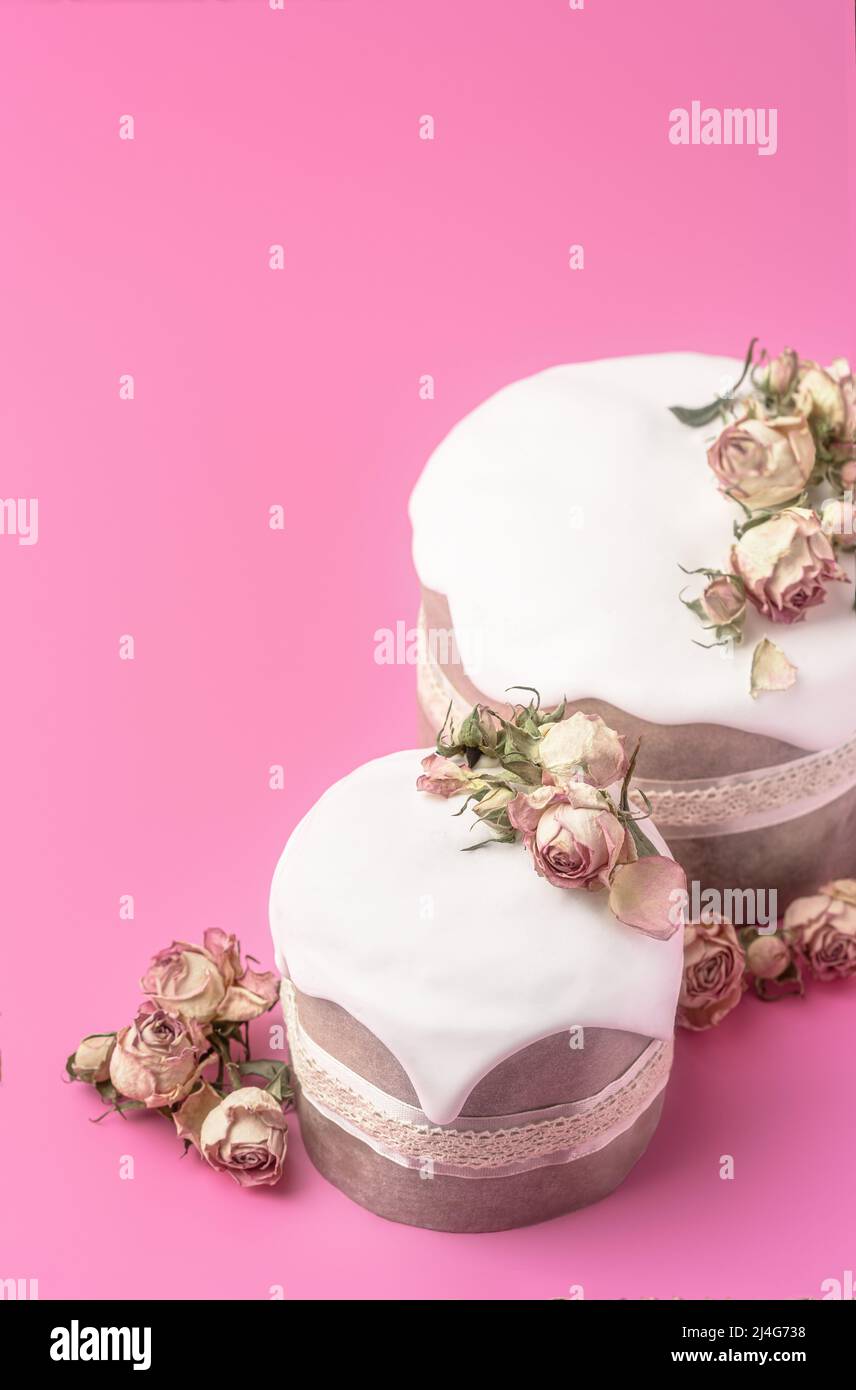 Gâteaux de Pâques vitrés décorés de fleurs de rose de thé sur fond rose vif. Composition de Pâques avec gâteaux, roses et œufs au chocolat. Arrière-plan de vacances avec espace de copie pour votre conception. Banque D'Images