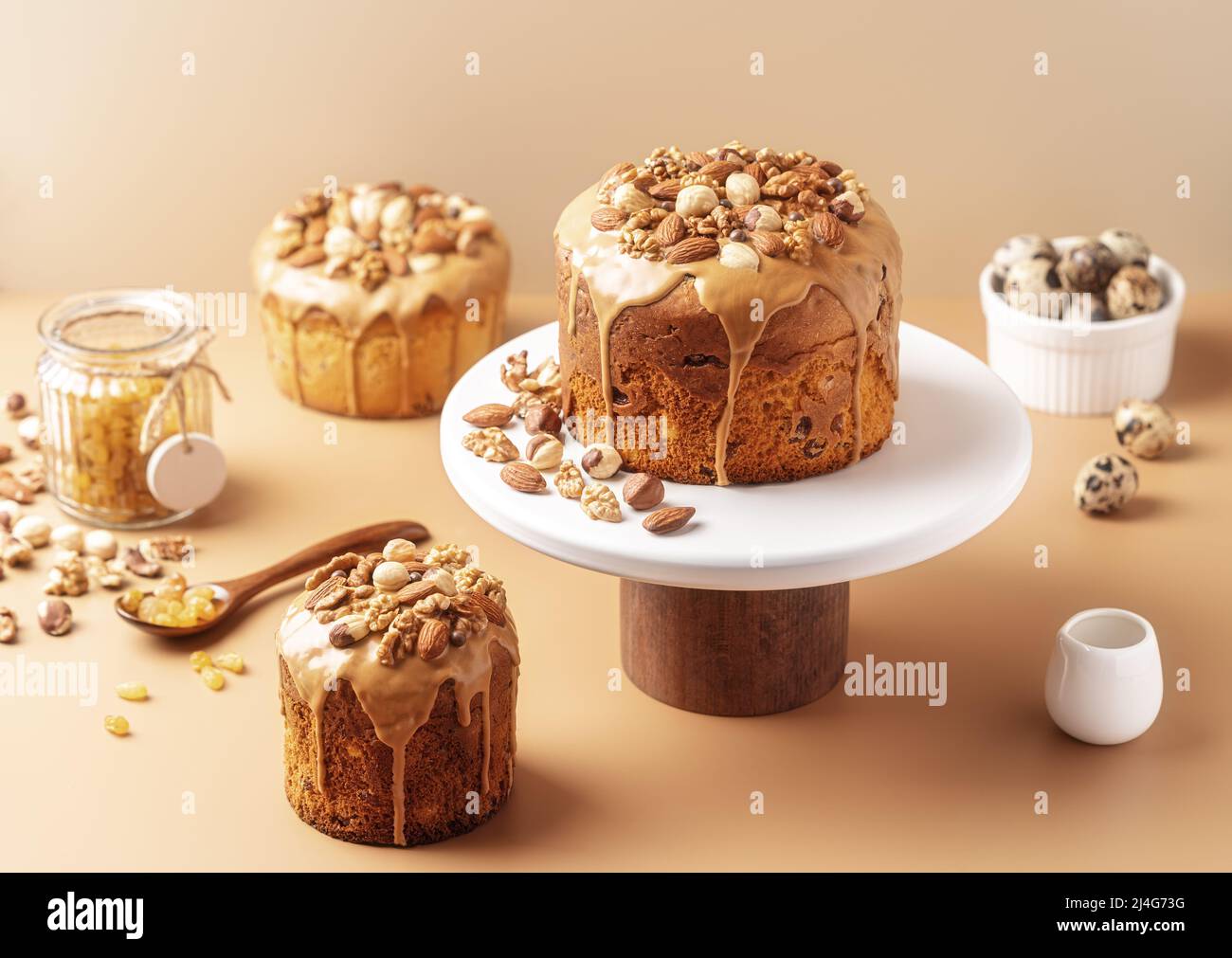 Gâteaux de Pâques émaillés de caramel décorés de noix sur fond pastel. Composition de Pâques avec gâteaux, noix, raisins secs et œufs de caille. Arrière-plan de Pâques avec espace de copie pour votre conception. Banque D'Images