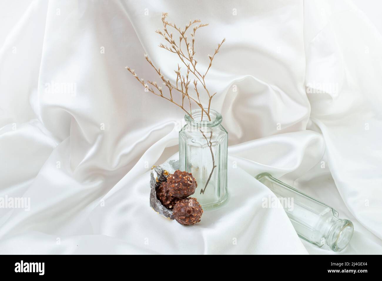 Boules de chocolat avec pots en verre et fond de satin blanc, photographie abstraite de produit. Banque D'Images