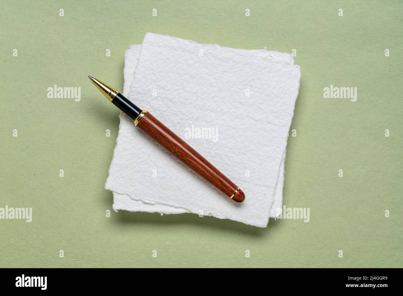 Petite feuille carrée de papier blanc Khadi vierge avec un stylo élégant contre du papier vert clair Banque D'Images