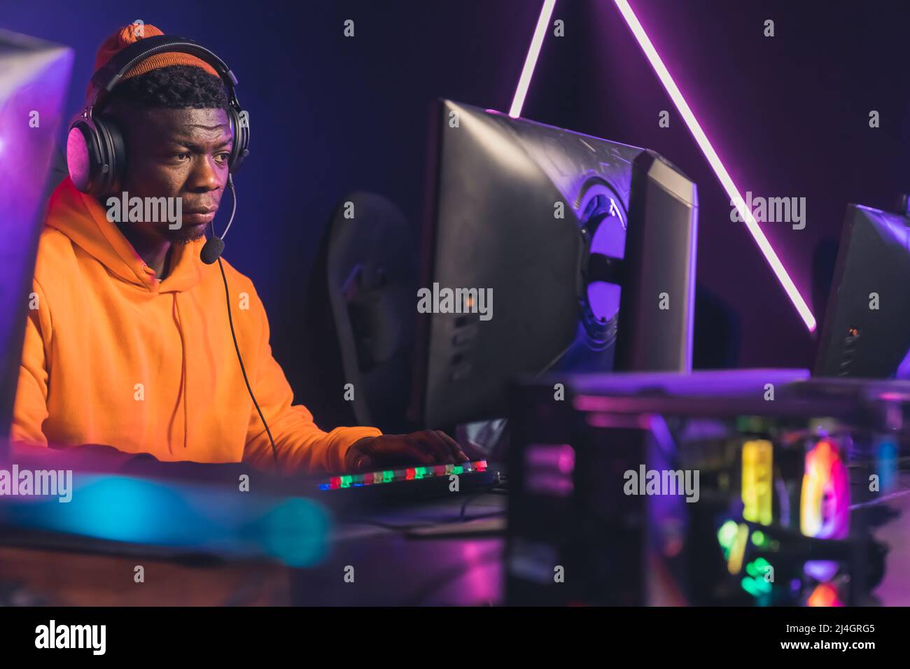 Joueur américain africain professionnel concentré sur la victoire dans les jeux vidéo en ligne tournoi de taille moyenne de gros plan de jeu batailles néon lumière à l'intérieur. Photo de haute qualité Banque D'Images