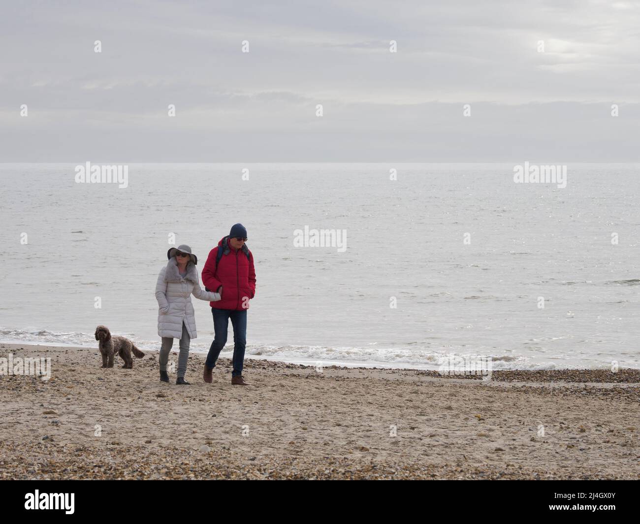 Couple marchant le long de la plage en mars, Highcliffe, Dorset, Royaume-Uni Banque D'Images
