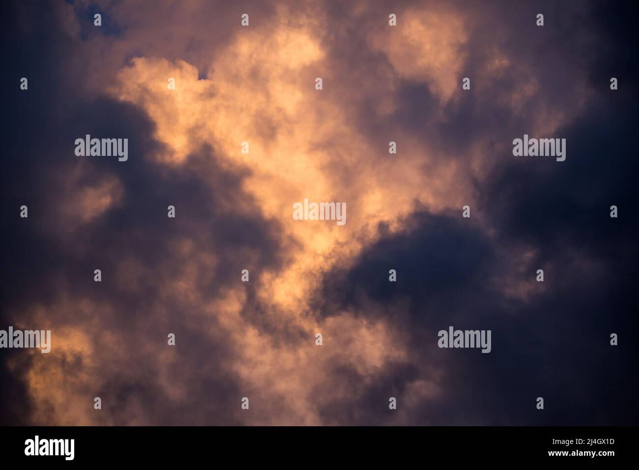 Les nuages de tempête sont illuminés dans un ton doré par le soleil couchant. Banque D'Images