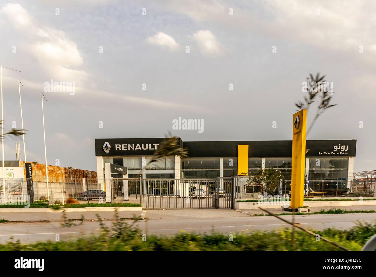 Concession de voitures Renault, Sarl Tabet Derraz Frères, bâtiment extérieur couleur jaune Brandmark panneau de logo en caractères arabes. Espace verrouillé et vide. Banque D'Images