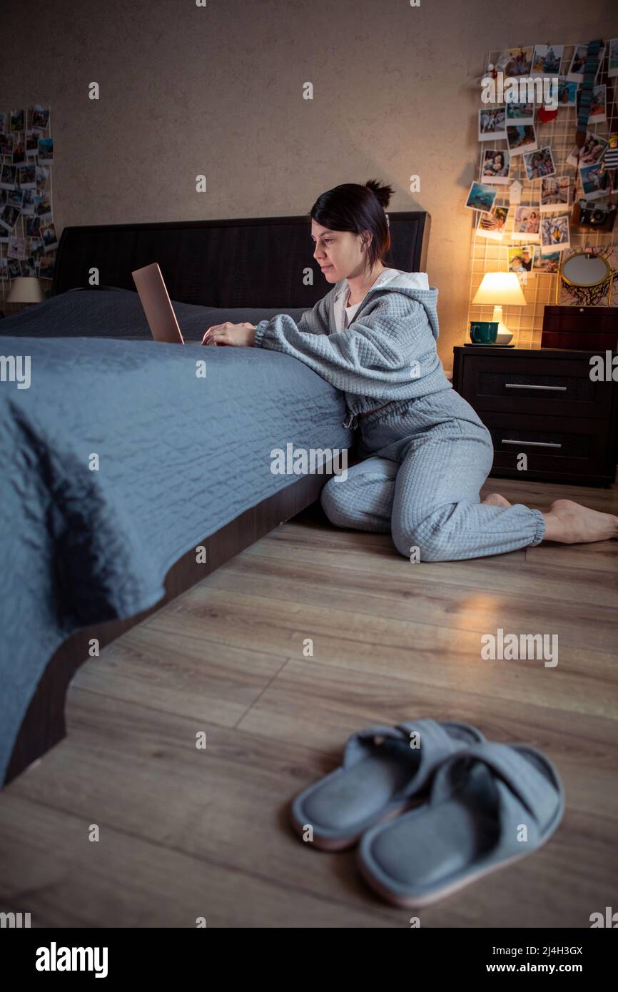femme indépendante travaillant à la maison sur ordinateur portable assis sur le plancher ordinateur portable sur le lit Banque D'Images