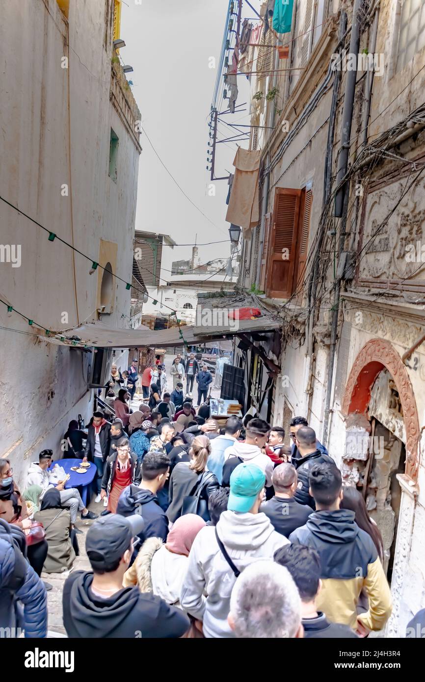Casbah, Alger : des gens bondés attendent dans la file pour des sardines de poissons grillés et du foie d'agneau dans un restaurant sauce. Vue en angle bas depuis l'arrière de la foule. Banque D'Images