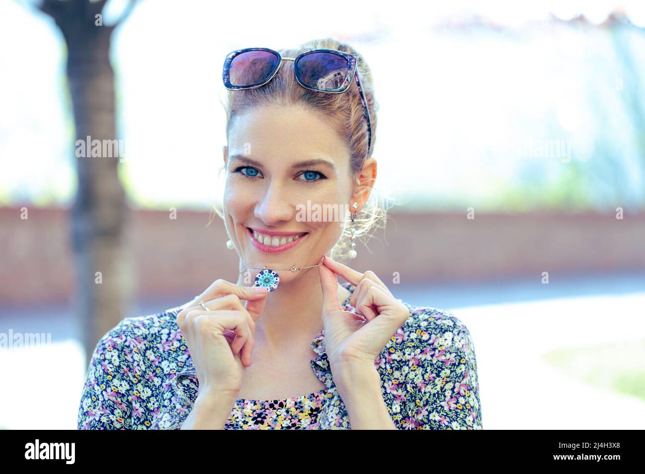 Jeune femme joyeuse tenant un collier bleu arrondi à l'extérieur Banque D'Images