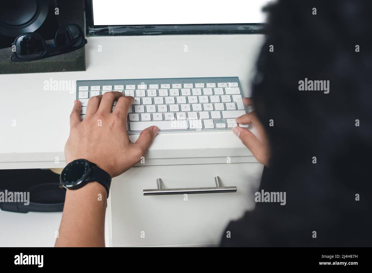 vue arrière de l'homme caucasien assis travaillant dans son bureau à la maison dactylographiant sur clavier d'ordinateur, la technologie et le concept indépendant. Banque D'Images