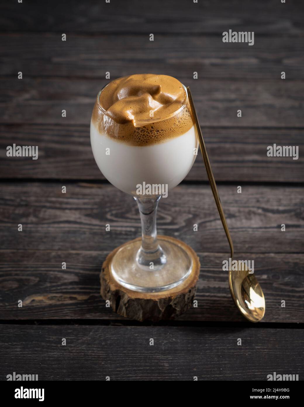 Le café Dalgona glacé, un café crémeux et moelleux tendance, sur fond de bois foncé avec une cuillère dorée Banque D'Images