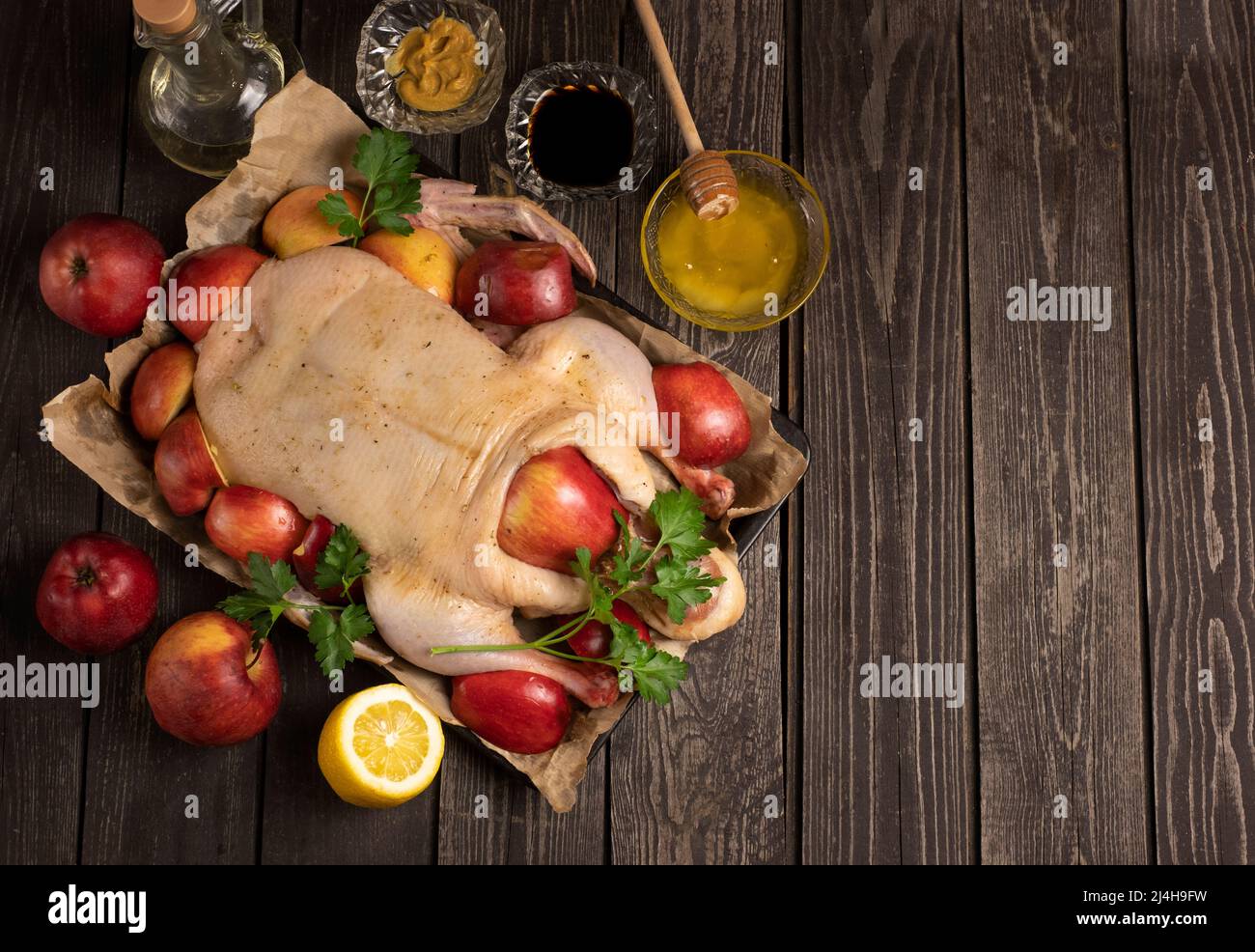 Jeunes canards entiers crus bio sur papier froissé avec sel et pommes rouges de jardinage sur fond de texture noire. Avec lindre mariné Banque D'Images
