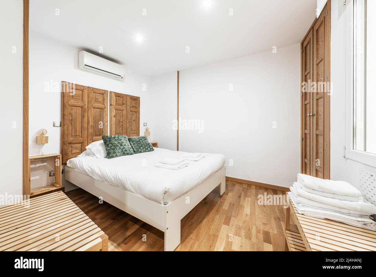 Chambre avec lit en bois avec couette blanche, têtes de lit en bois  récupérées, parquet en chêne et armoire intégrée avec portes assorties  Photo Stock - Alamy