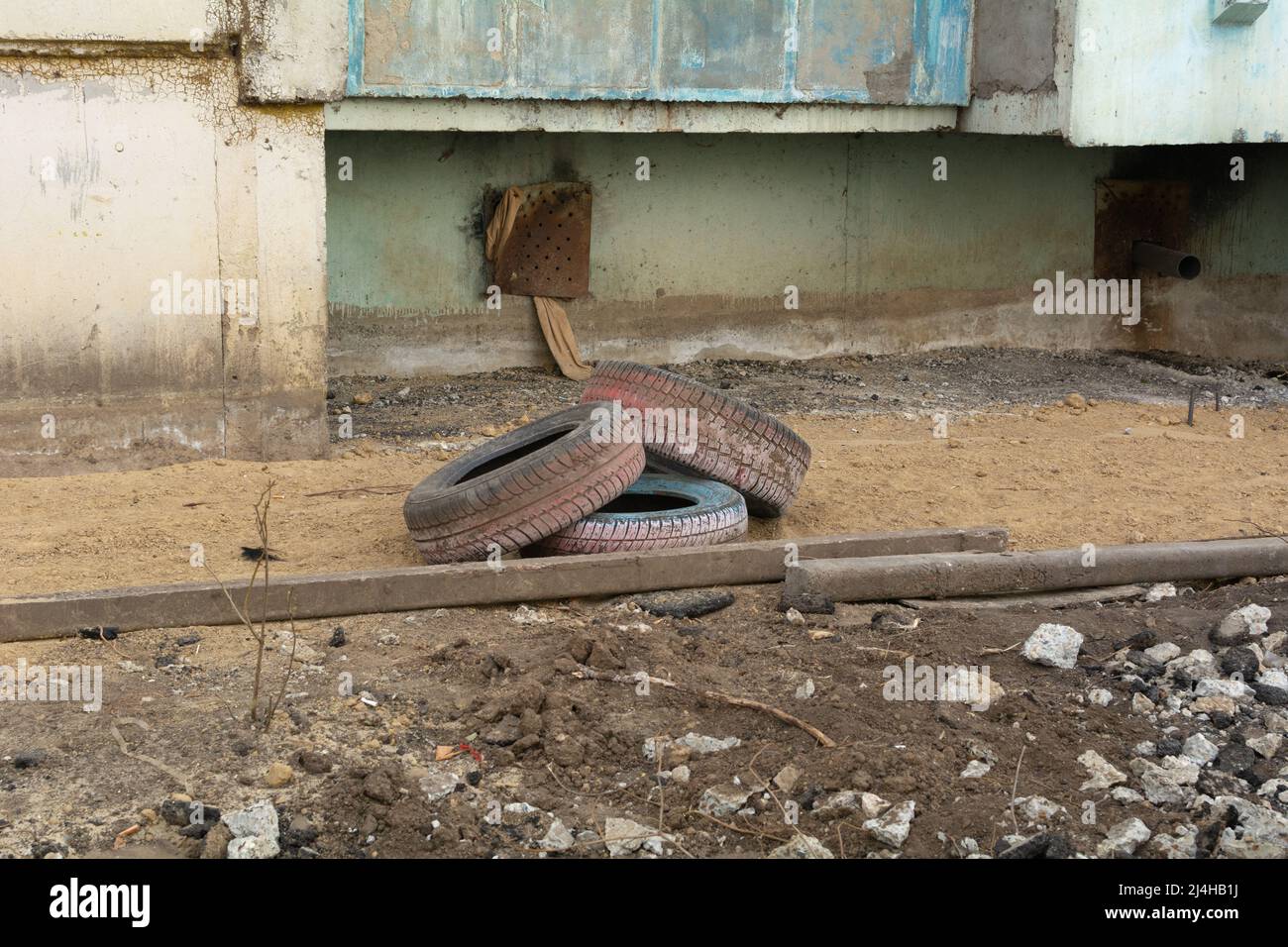 Les vieux pneus de voiture d'occasion se trouvent à proximité d'un bâtiment résidentiel. Le problème de l'écologie et du traitement des matières premières. Banque D'Images
