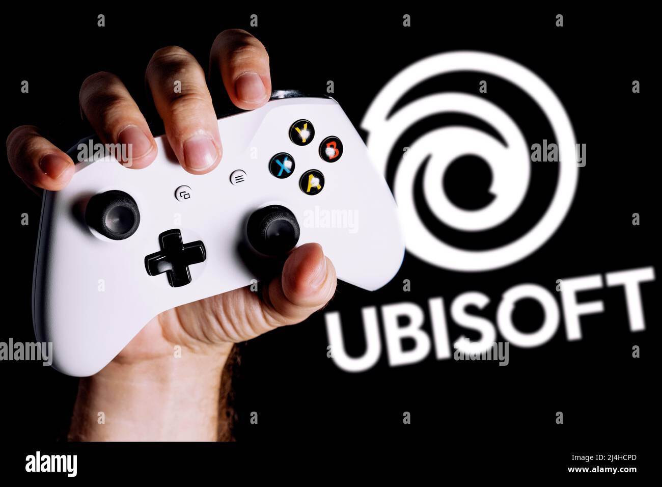 Ubisoft est une société française de jeux vidéo. Manette de jeu accrochée à la main sur fond noir avec le logo d'Ubisoft. Banque D'Images