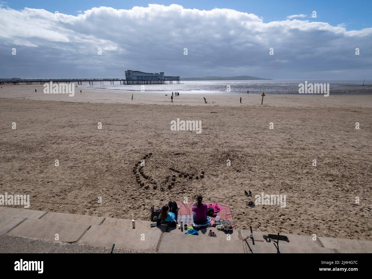 Les vacanciers apprécient la plage de Weston Super Mare avec le Grand Pier dans le Bristol Chanel, Somerset. Banque D'Images