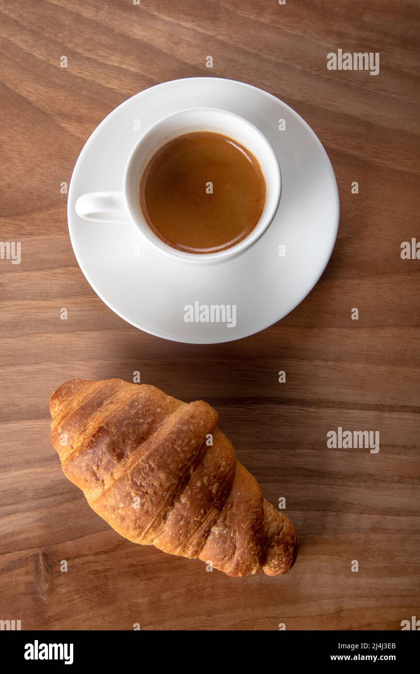 Croissant avec espresso dans une tasse blanche, vue de dessus Banque D'Images