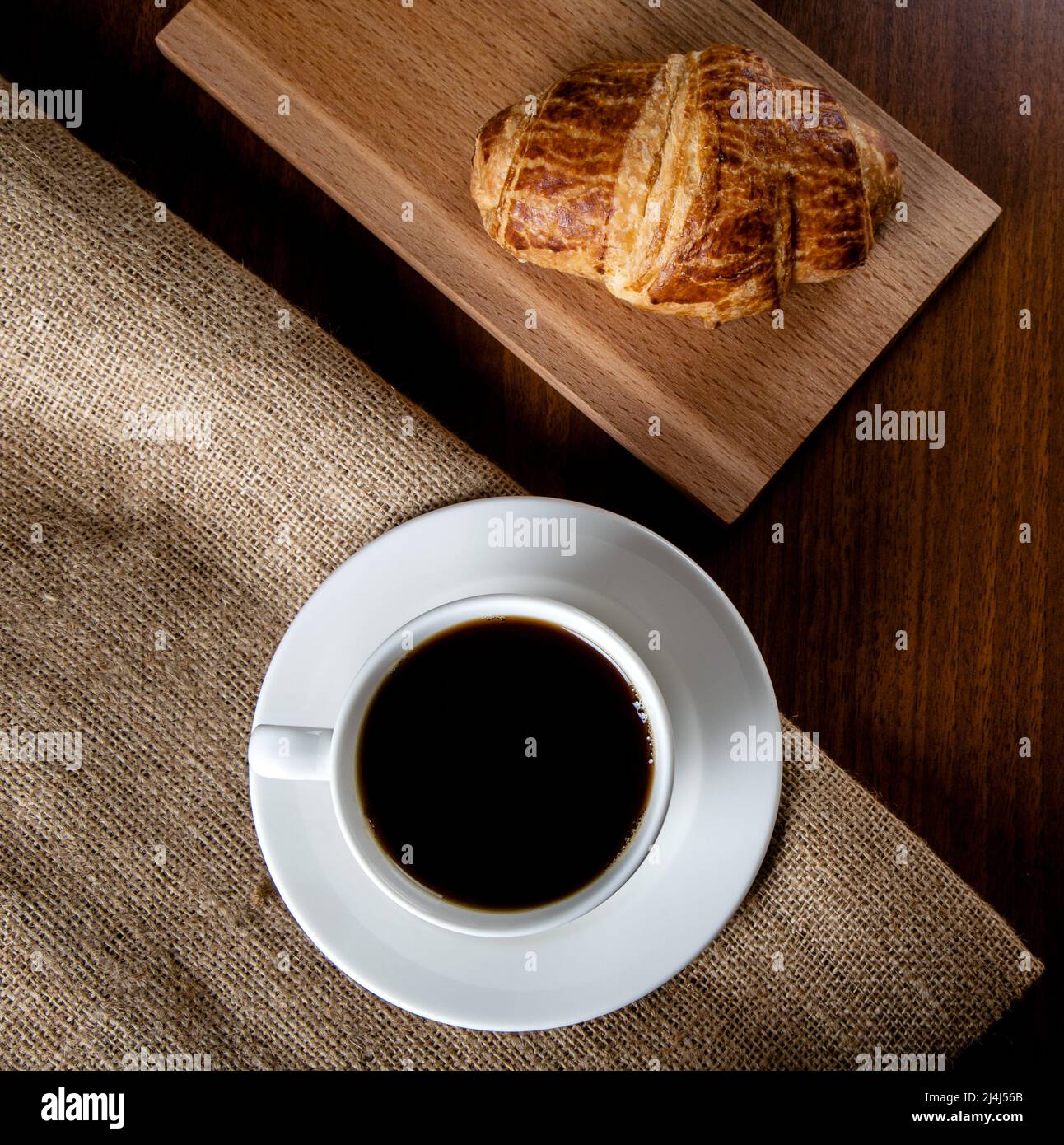 Tasse blanche pleine de café filtre et croissant, vue de dessus Banque D'Images