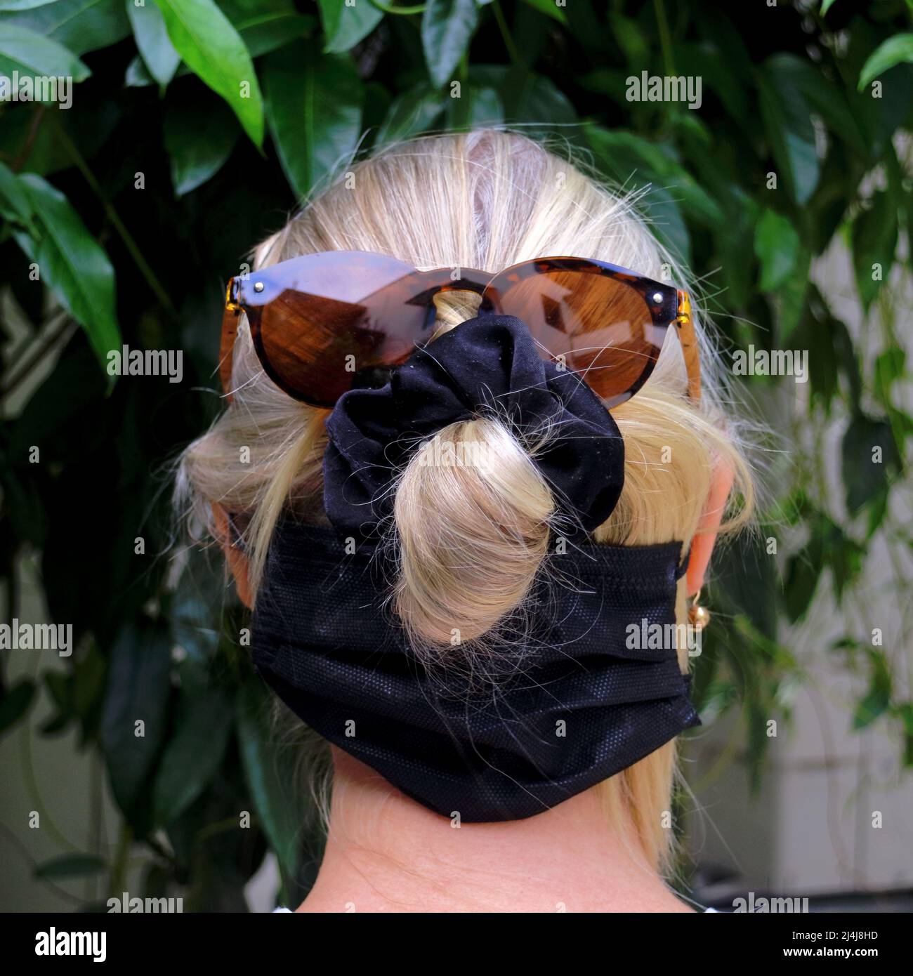 Dos d'une tête de femme blonde portant des lunettes de soleil et scrunchie Banque D'Images