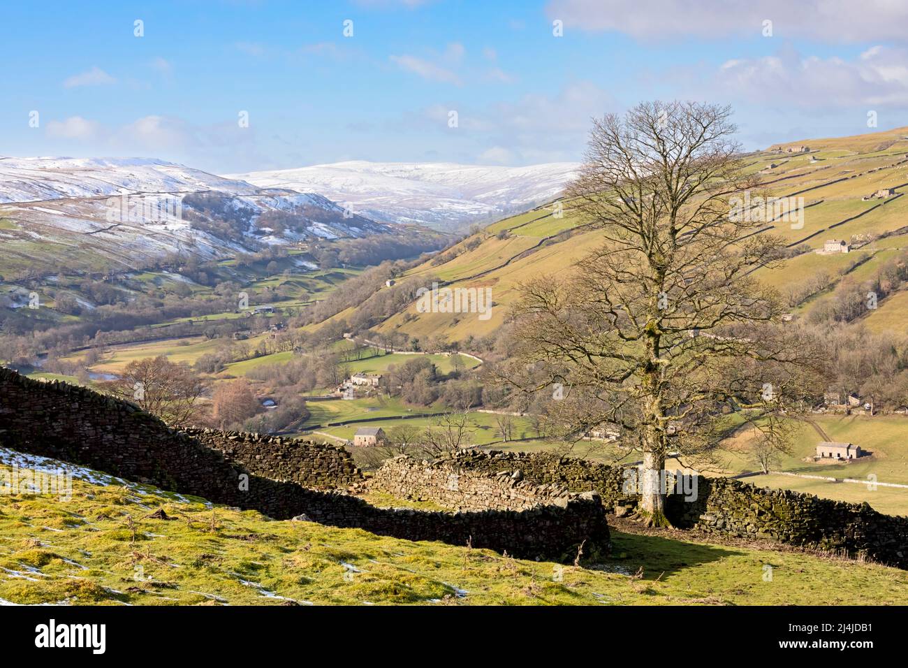 Swaledale, parc national de Yorkshire Dales, collines enneigées au-dessus d'une mosaïque de champs et de pâturages bordés de murs de pierre sèche avec des granges en pierre emblématiques Banque D'Images