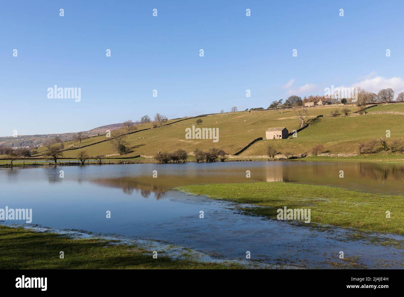 Champs inondés près de Reeth à Swaledale, dans le parc national de Yorkshire Dales. La grange emblématique en pierre et les murs en pierre sèche se reflètent dans l'eau fixe. Banque D'Images