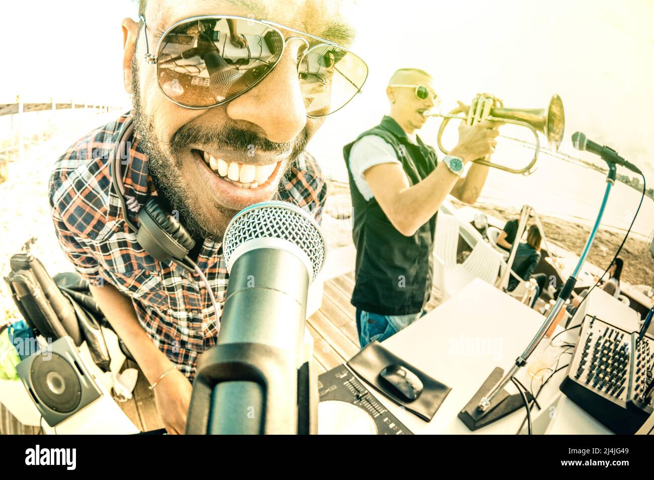 DJ jouant des tubes d'été au coucher du soleil sur la plage avec un  interprète de trompette jazz - concept de vacances au club en plein air avec  musique maison au lieu